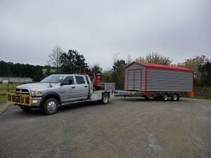 Red and gray metal shed hauled by truck