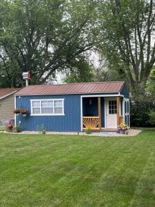 Blue shed with porch and landscaping