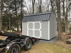 Gray shed being delivered by truck