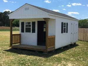 White shed with porch in backyard