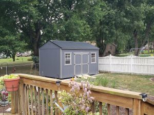 Old Hickory Side Utility Shed with double barn doors, windows, metal roof and ramp in spring backyard, portable storage building