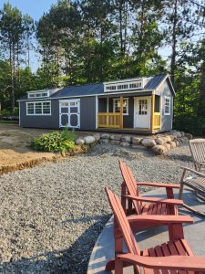 Old Hickory Utility Shed with Side Porch, Shed Dormers and double barn doors next to gravel patio with fire pit